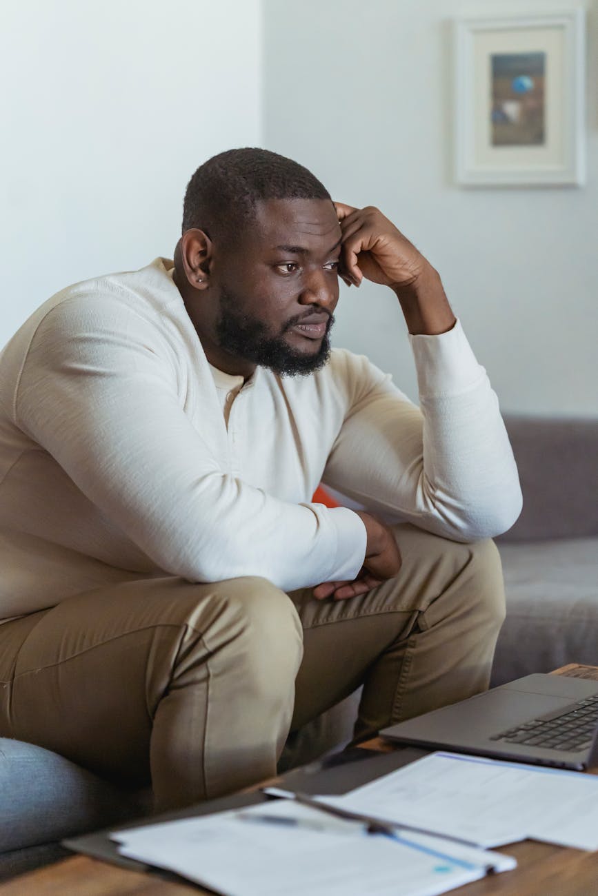 frustrate black man sitting near laptop and thinking